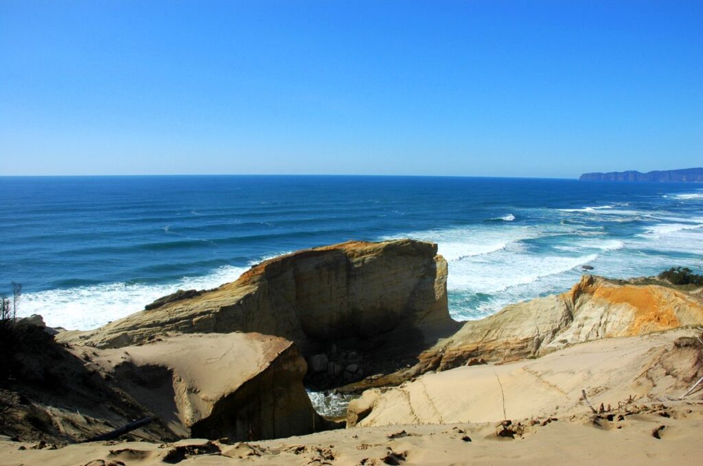 Wind-carved sandstone ledges at the edge of a cape above a churning blue ocean