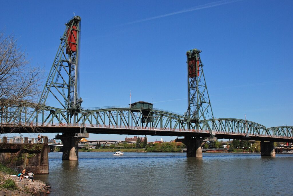 The green Hawthorne Bridge and its two lift towers spanning the Willamette River under a clear sky