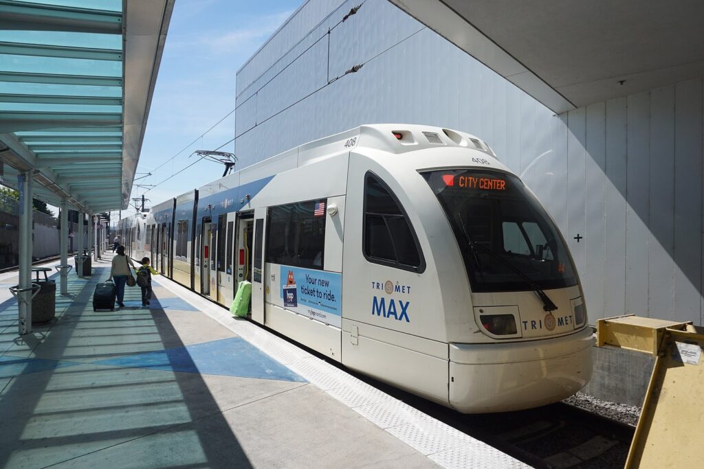 A white MAX train marked City Center waiting under the canopy of the Portland International Airport station
