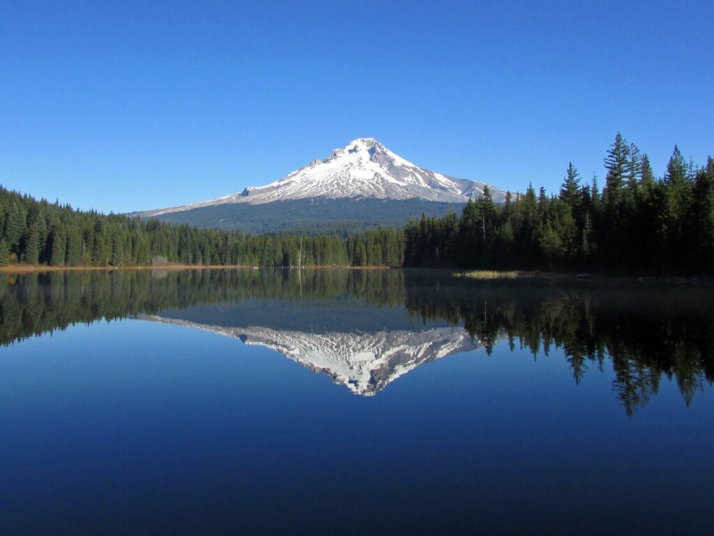 Snow-capped Mount Hood reflected in the still water of Trillium Lake under a clear blue sky