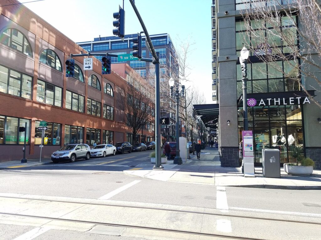 A Pearl District street corner with brick warehouse buildings, shopfronts and a streetcar track