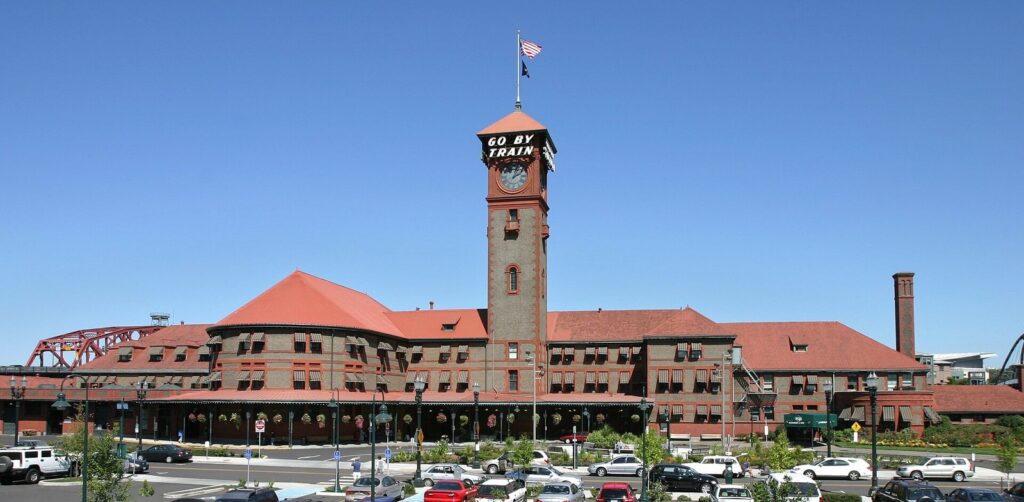 The brick clock tower of Portland Union Station, topped by a Go By Train sign, against a clear blue sky