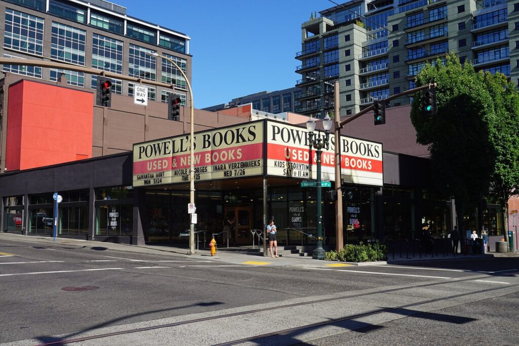 The red and white marquee of Powell's City of Books wrapping a street corner beneath apartment towers