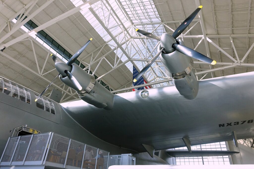 The huge silver wing, engines and propellers of the Spruce Goose flying boat inside a glass-walled museum hangar