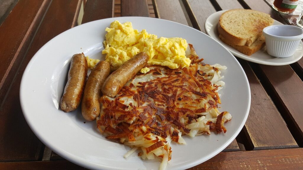 A diner breakfast of scrambled eggs, link sausages and crisp hash browns with toast on the side