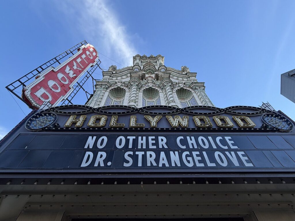 The ornate terra-cotta facade and marquee of the Hollywood Theatre, with its name in large letters above a film listing