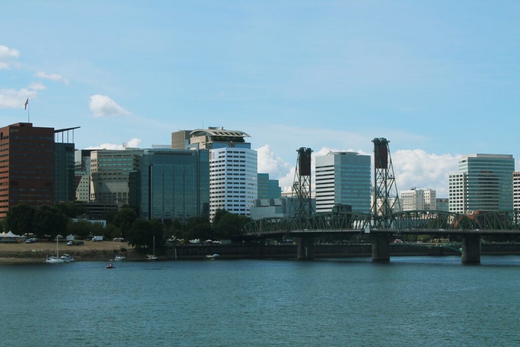 The green steel Hawthorne Bridge and its two lift towers crossing the Willamette River in front of downtown Portland's office towers